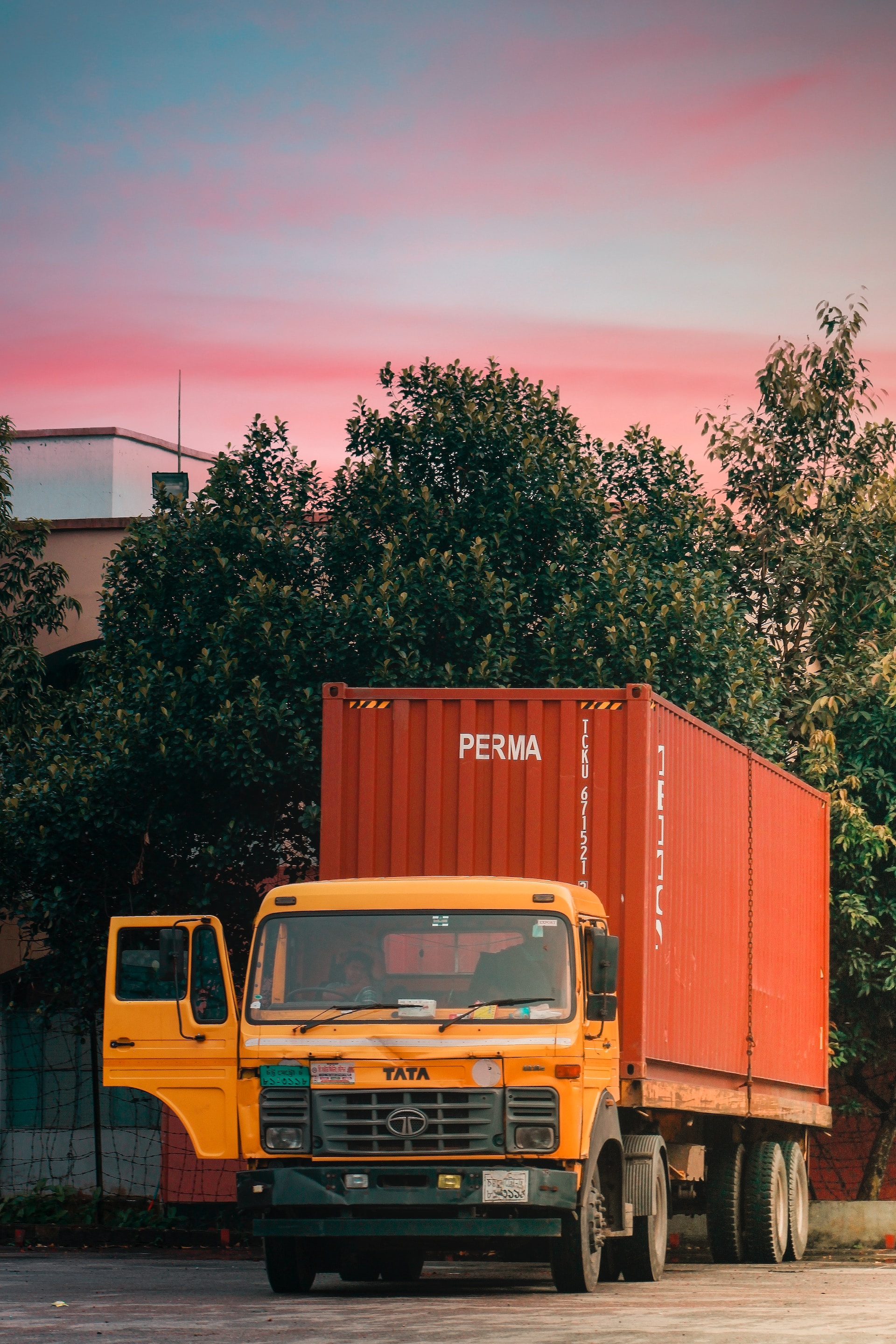 A large orange truck drives down the road Description automatically generated with medium confidence